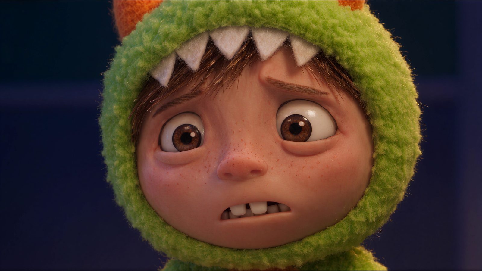 His little brother, in a green monster hood, looks on in worry